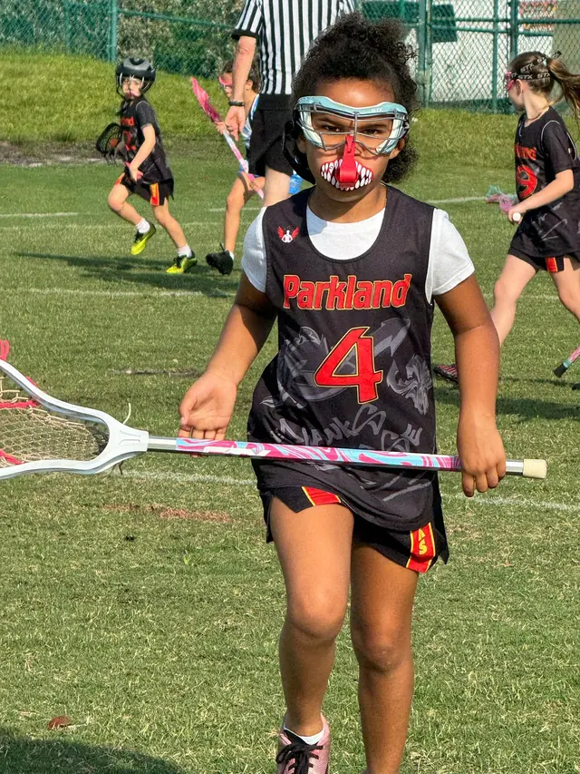 A Redhawks girl in goggles running with her stick